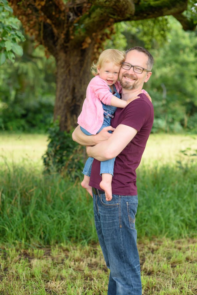 Vater hält seine Tochter unter einem Baum auf dem Arm