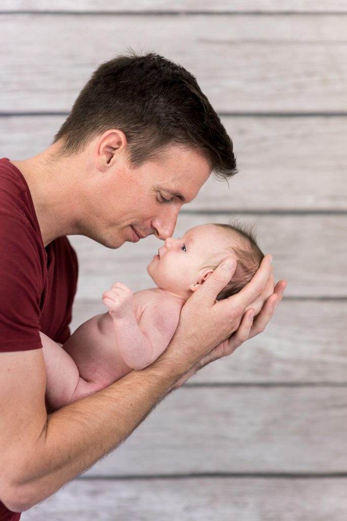 Vater hält sein Neugeborenes und berührt es mit der Nase