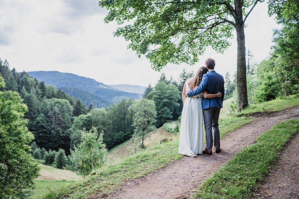 Brautpaar umarmt sich auf einem Feldweg mit Blick über die Hügel